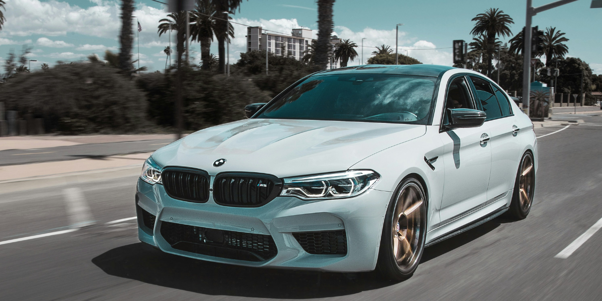 En vit BMW på solig gata.