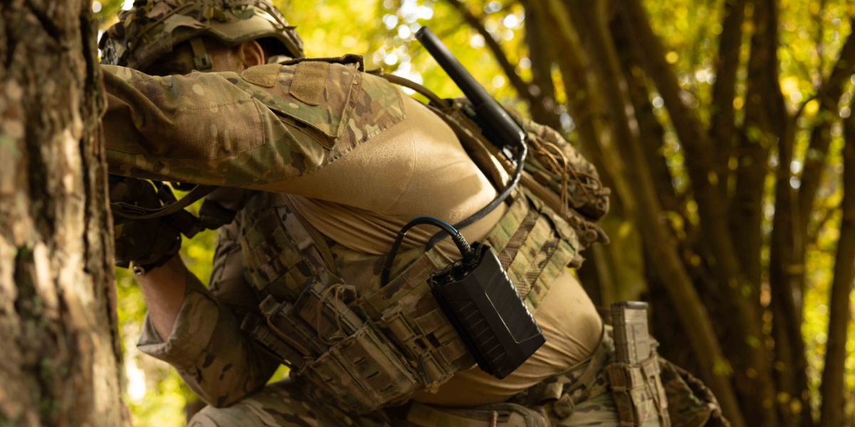 En militärklädd person i skogen spanar.