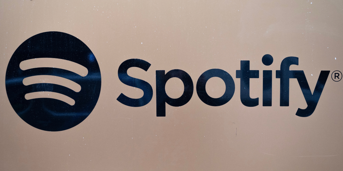 Spotifys logotyp i svart på en beige vägg.